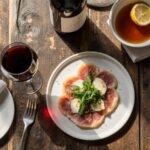 Rezeptidee Wein zum Essen Modern angerichtetes Rinder-Carpaccio mit Parmesan und Zitronen-Olivenöl und ein Glas Barbera