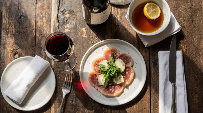Rezeptidee Wein zum Essen Modern angerichtetes Rinder-Carpaccio mit Parmesan und Zitronen-Olivenöl und ein Glas Barbera