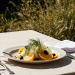 Rezeptidee Wein zum Essen Fenchelsalat mit Orange auf Keramikteller, mediterraner Tisch, Vermentino-Wein