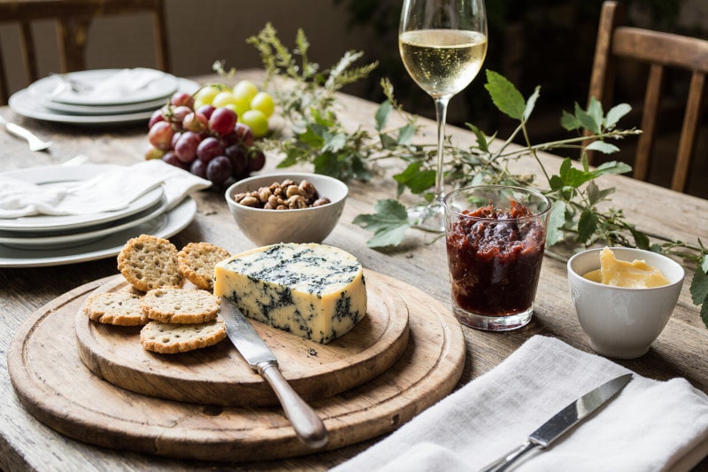Wein zum Essen Blauschimmelkäse mit Trauben-Chutney, Sauerteigcrackern & Chardonnay auf französischem Landhaustisch