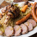 Wein zum Essen Choucroute Garnie mit Wurst, Fleisch, Sauerkraut & Riesling d’Alsace auf französischer Landtafel
