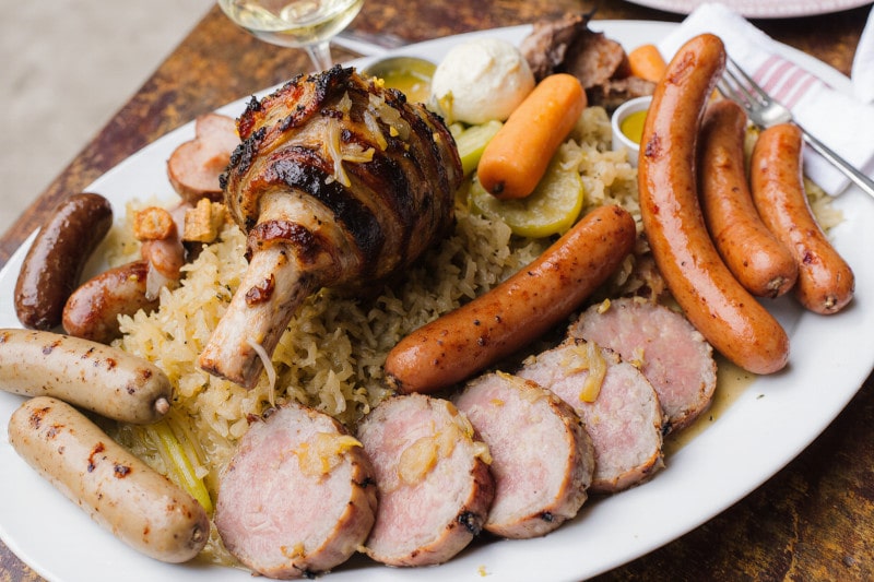 Wein zum Essen Choucroute Garnie mit Wurst, Fleisch, Sauerkraut & Riesling d’Alsace auf französischer Landtafel