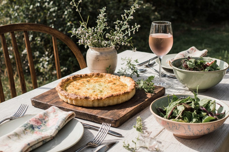 Wein zum Essen Quiche Lorraine, französischer Landhaus-Gartentisch mit Rosé und Kräutern