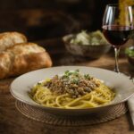 Wein zum Essen – Linsen-Pilz-Bolognese mit Kräutern und Pecorino auf rustikalem Holztisch mit Chianti-Glas
