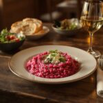 Wein zum Essen – Rote-Bete-Risotto mit Meerrettich und Ziegenkäse auf Holztisch mit Pinot Gris Glas