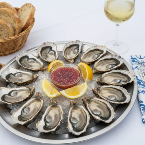 Wein zum Essen: Frische Austern aus Arcachon auf Eis neben einem Glas Entre-deux-Mers Weißwein.