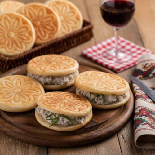 Wein zum Essen: Warme Tigelle mit Cunza neben einem Glas Lambrusco Rotwein.