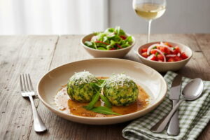 Wein zum Essen: Grüne Bärlauch-Knödel mit Nussbutter neben einem Glas Silvaner Weißwein.