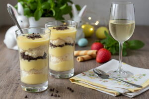 Eine cremige Eierlikör-Mousse mit Schokosplittern im Glas neben einem eleganten Glas Moscato d’Asti Wein.