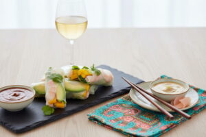 Wein zum Essen: Frische Glücksrollen mit Mango neben einem Glas Gelber Muskateller Wein.