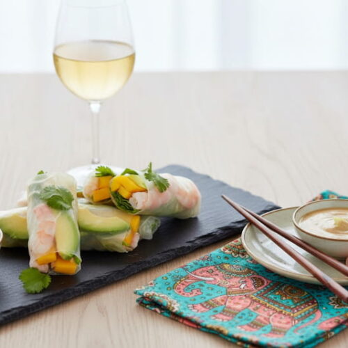 Wein zum Essen: Frische Glücksrollen mit Mango neben einem Glas Gelber Muskateller Wein.
