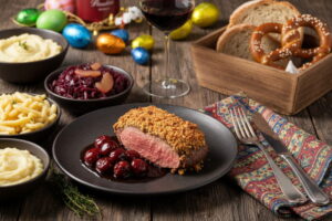 Wein zum Essen: Rosa gebratener Rehrücken mit Haselnusskruste, Kirschsauce und einem Glas Primitivo Rotwein.