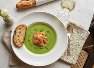 Kalte Erbsen-Minz-Suppe mit Lachsforellen-Tatar in mattem Suppenteller, Sancerre Weißweinglas, Pariser Bistro-Setting