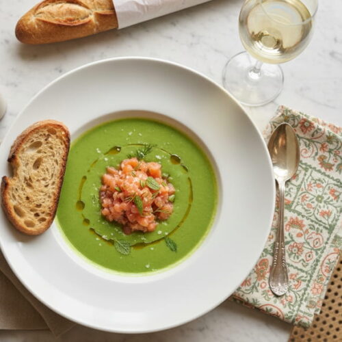 Kalte Erbsen-Minz-Suppe mit Lachsforellen-Tatar in mattem Suppenteller, Sancerre Weißweinglas, Pariser Bistro-Setting